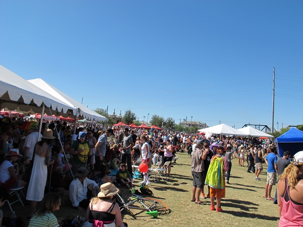 Photo is of the festival area where there are a lot of people and tents set up for various things.