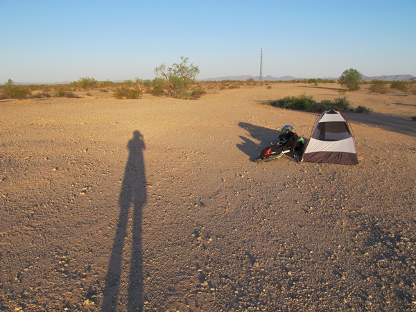 Photo is of our tent with the tandem next to it on a desert ground where it's just hard packed dirt with small shrubbery.